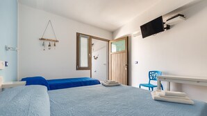 A bedroom with two beds, a TV mounted on the wall, a wooden door, and a blue chair. - 2132 Maresidence - Camere Triple (Salve)