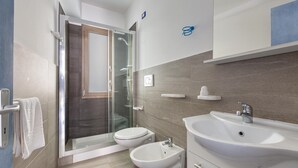 A modern bathroom with a glass-enclosed shower, two toilets, a bidet, and a large sink. - 2132 Maresidence - Camere Triple (Salve)