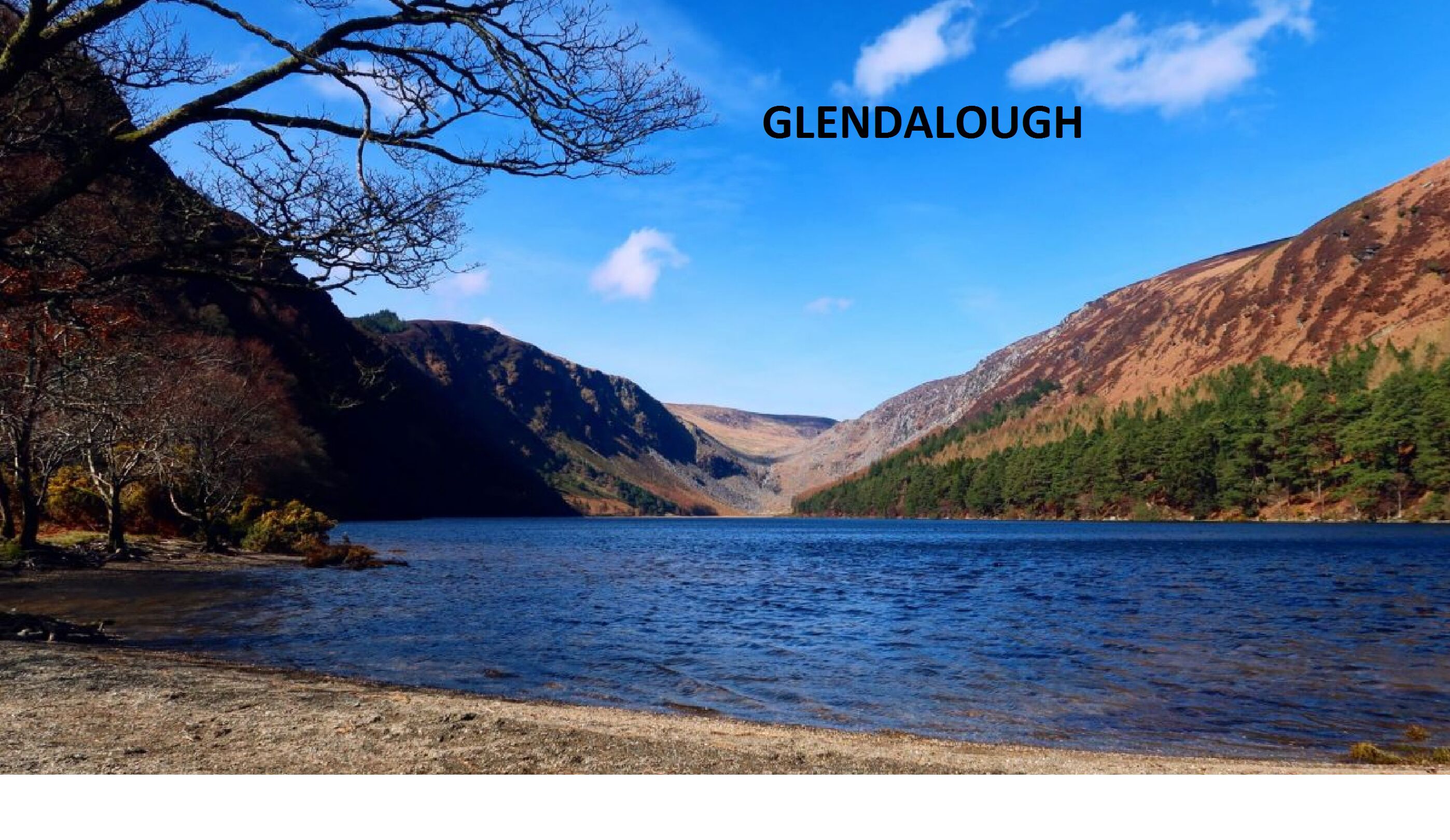 A scenic view of Glendalough with a lake surrounded by hills and trees.