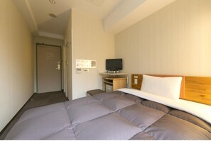 A hotel room with a bed, a television, a desk, and a door.