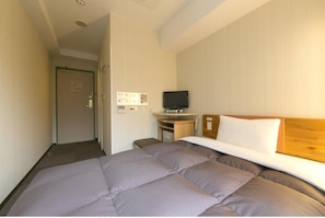 Ein Hotelzimmer mit Bett, Fernseher, Schreibtisch und Tür.