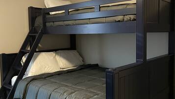 Un lit superposé avec une échelle, un oreiller et une couverture.