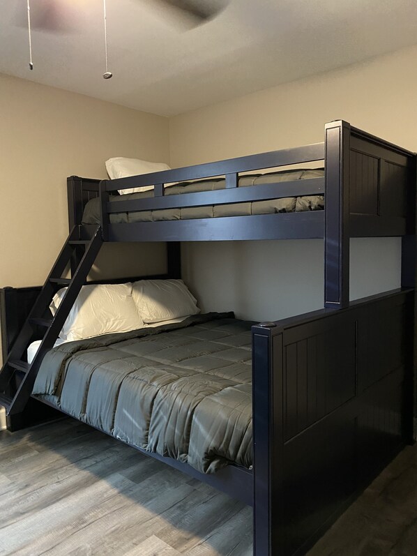 Una cama litera con escalera, un almohadón y una manta.