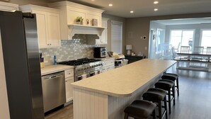 A modern kitchen with a central island, stainless steel appliances, and a dining area with a view.
