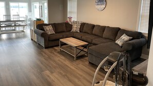 A modern living room with a sectional sofa, a coffee table, and a fan.