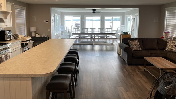 A modern kitchen with a central island, bar stools, and a dining area with white chairs.