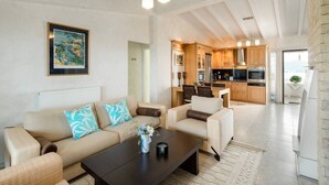 A spacious living area with a sofa set, a coffee table, and a painting on the wall. - Beautiful and Modern Apartment in Neos Marmaras (Sithonia)