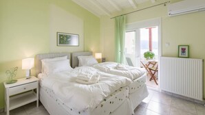 A bedroom with a large bed, two bedside tables, a radiator, and a window with curtains. - Beautiful and Modern Apartment in Neos Marmaras (Sithonia)