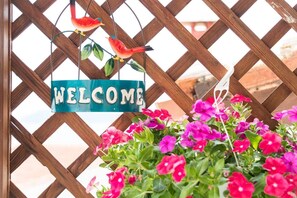A wooden lattice structure with a 'WELCOME' sign and colorful flowers. - Beautiful and Modern Apartment in Neos Marmaras (Sithonia)