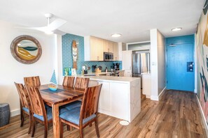 A modern kitchen with white cabinets, a central island, and a blue door.