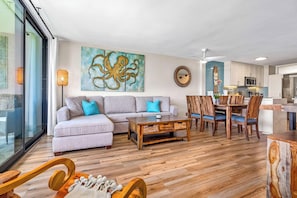 A modern living room with a sofa, coffee table, and dining area.