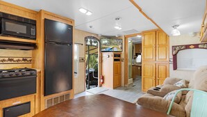 Eine kompakte Küchenzeile für Wohnmobile mit Mikrowelle, Herd, Kühlschrank und Essbereich.