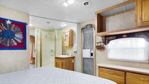 Ein Schlafzimmer mit einem Bett, einem Holzschrank und einem Schminktisch mit Spiegel.