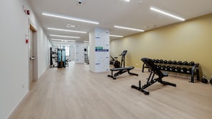 A modern gym with exercise equipment, a bench, and dumbbells. - Camplus Regio Parco (Turin)