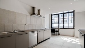 A modern kitchen with a large window, a dishwasher, and a dining area with a table and chairs. - Camplus Regio Parco (Turin)
