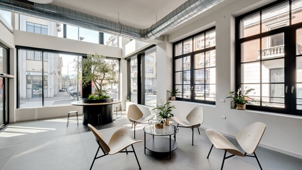 A modern interior with large windows, a round glass table, and contemporary chairs. - Camplus Regio Parco (Turin)
