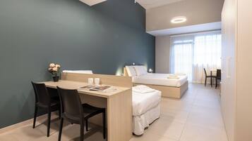 Habitación de hotel moderna con escritorio, dos sillas, una cama y una mesita con una planta.