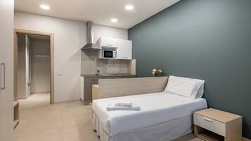 Ein modernes Schlafzimmer mit Bett, Nachttisch und einer integrierten Küchenzeile.