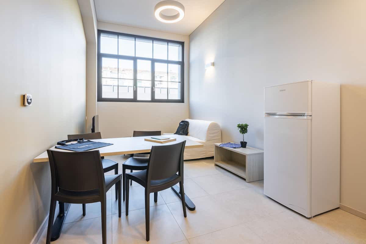 A modern kitchen with a dining table, chairs, a refrigerator, and a window providing natural light.