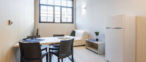 A modern kitchen with a dining table, chairs, a refrigerator, and a window providing natural light.