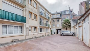 Eine enge Straße mit Gebäuden an beiden Seiten, ein geparktes Auto und ein Baum.