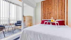 Una camera d'albergo con un letto, un piccolo tavolo con un cuscino rosso, una sedia e un pannello in legno.