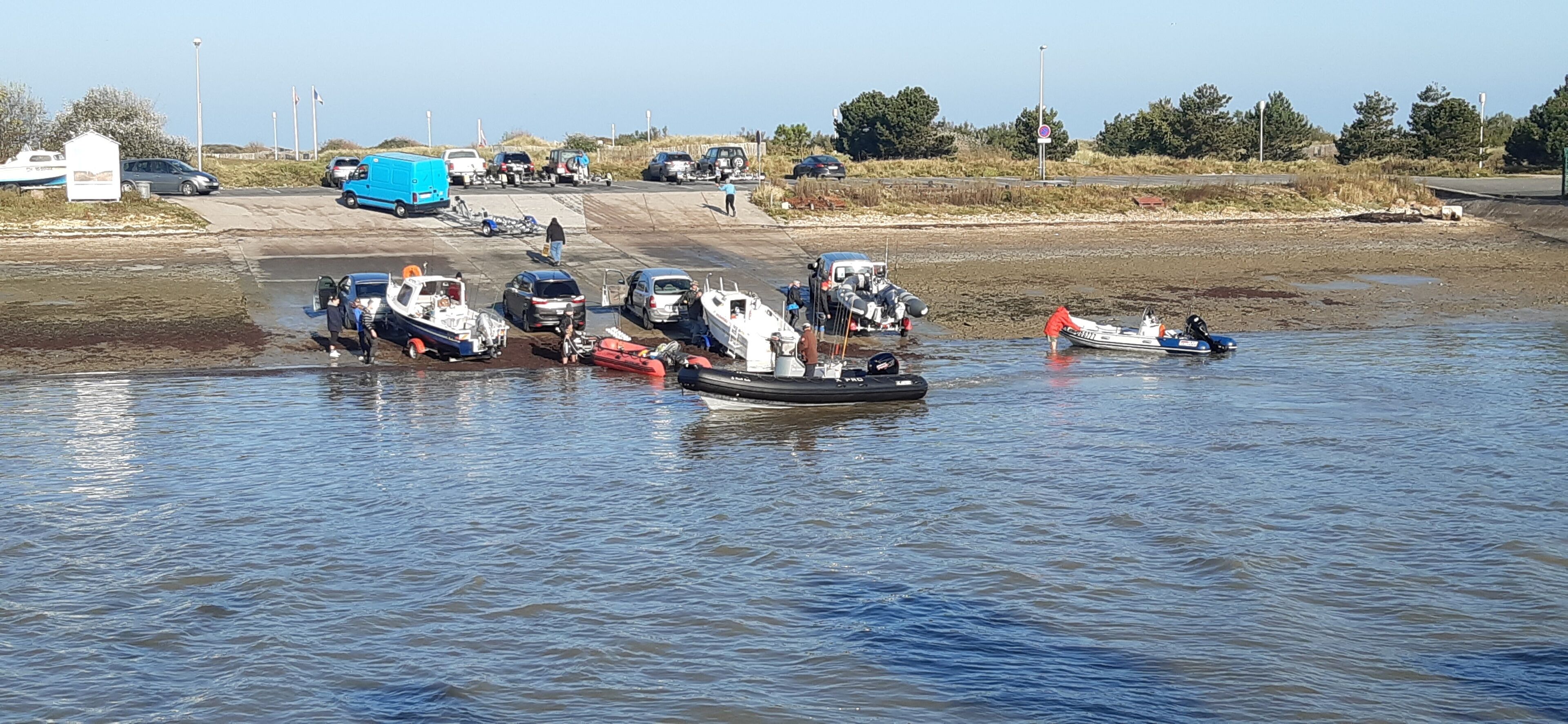 A waterfront area with several boats and vehicles docked near the shore.