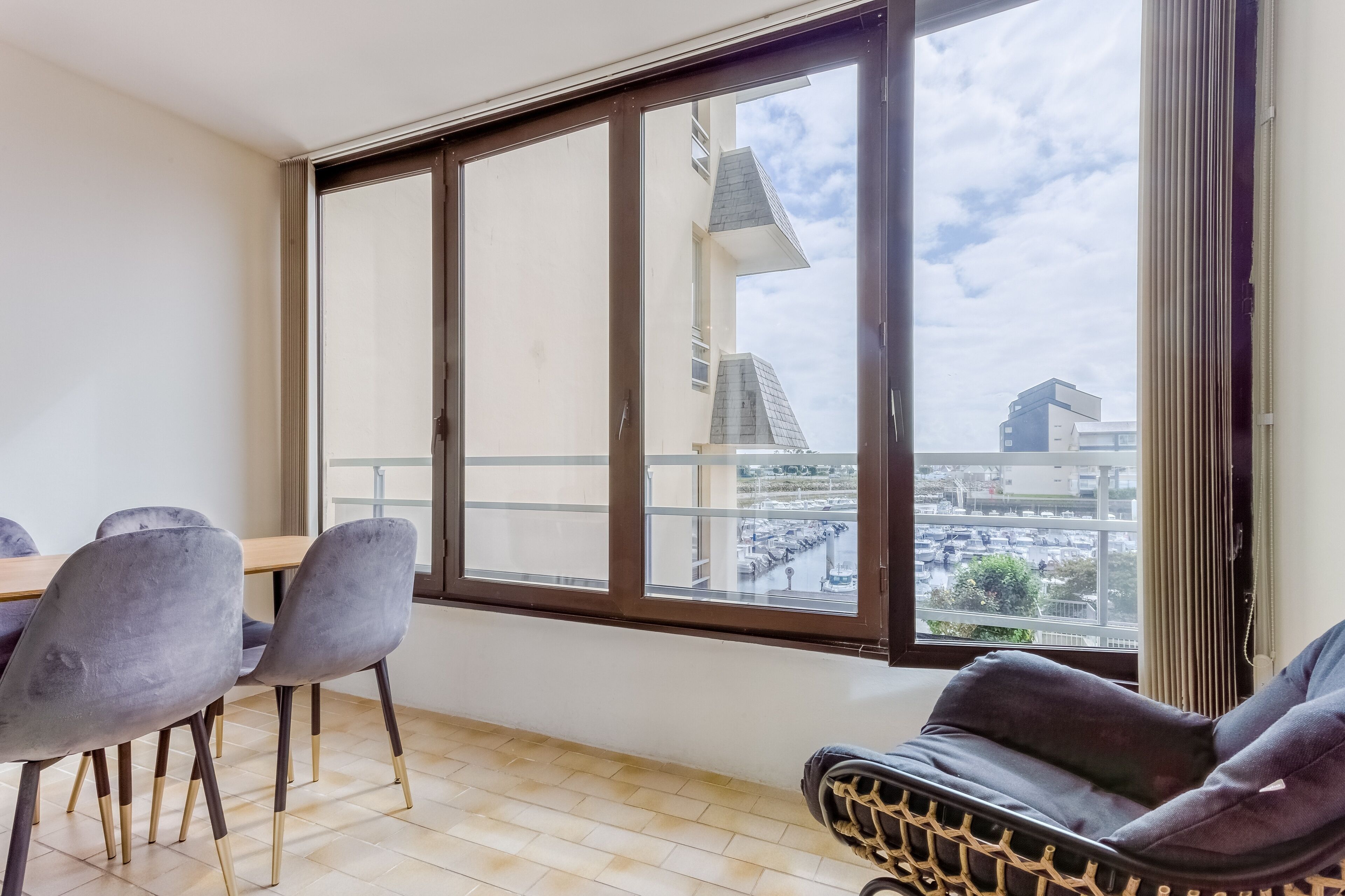 A room with a large window, a dining table with chairs, and a sofa.