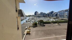 Una vista di una marina con barche ormeggiate, un'area parcheggio e moderni edifici residenziali sullo sfondo.