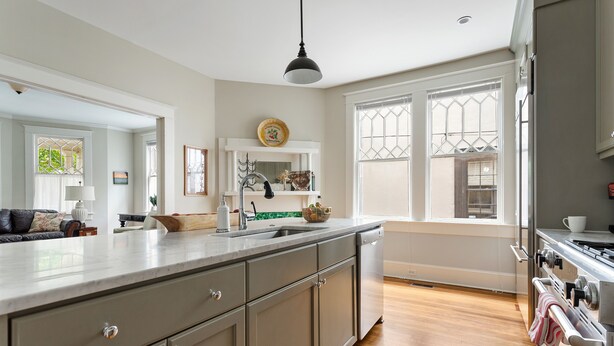 A kitchen with a large island, wooden cabinets, a built-in oven, and a window with a view of the outdoors. - Downtown Luxury | Rutledge Avenue Inn (Suite A) (Charleston)