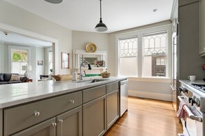 A kitchen with a large island, wooden cabinets, a built-in oven, and a window with a view of the outdoors. - Downtown Luxury | Rutledge Avenue Inn (Suite A) (Charleston)