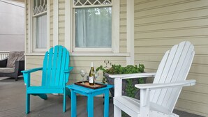 A porch with two Adirondack chairs, a small table with a tray, and a bottle of wine. - Downtown Luxury | Rutledge Avenue Inn (Suite A) (Charleston)