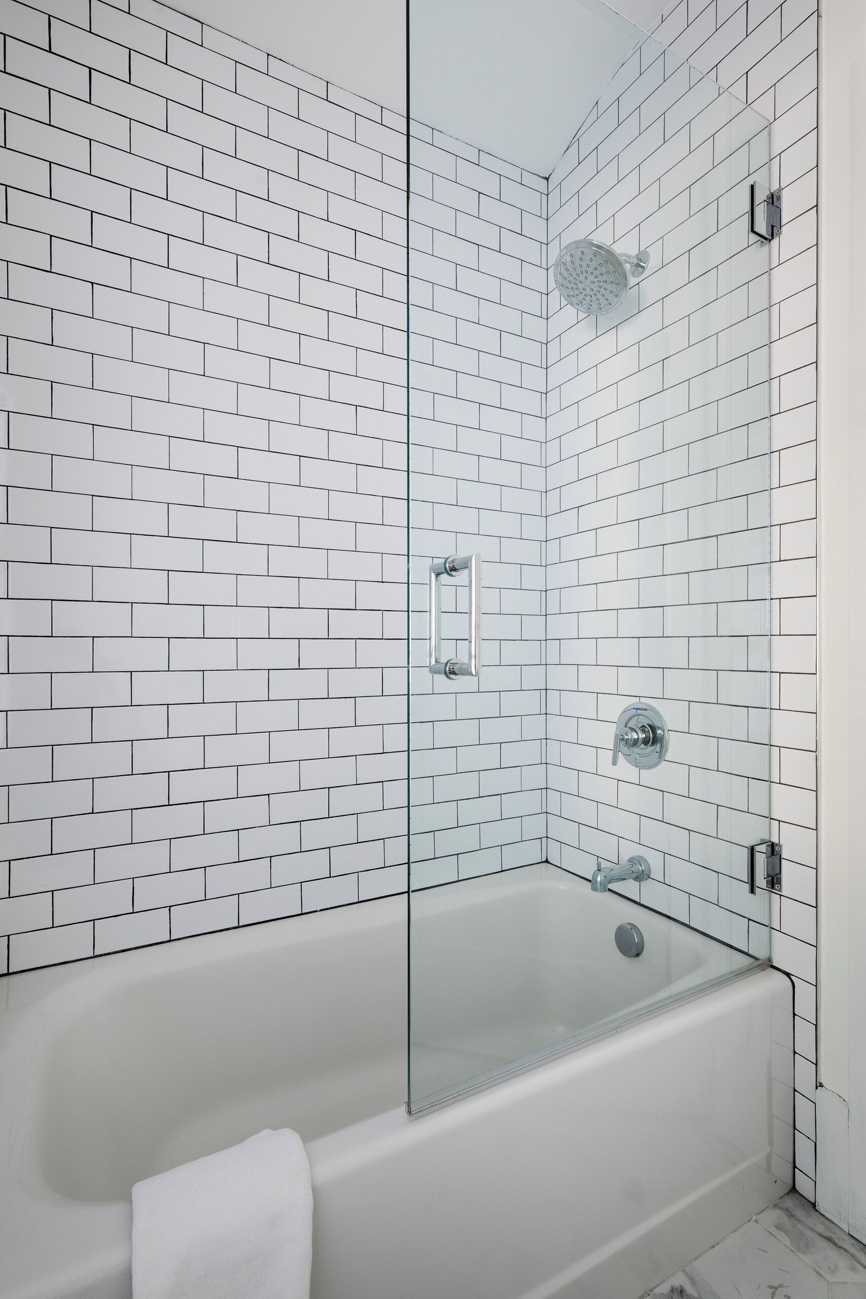 A modern bathroom with white subway tiles, a glass-enclosed shower, and a standalone bathtub.