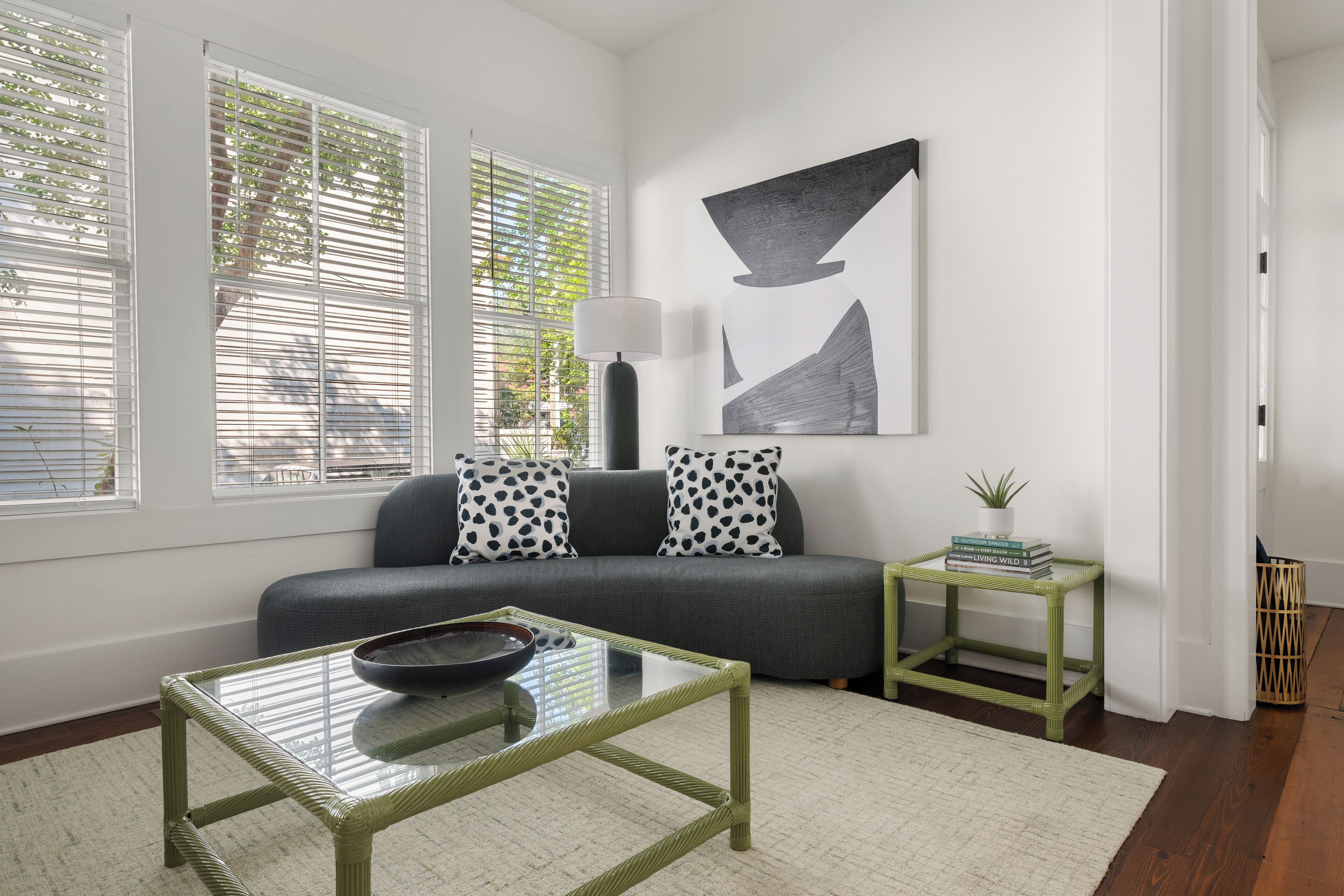 A modern living room with a sofa, a glass coffee table, and a side table with books.