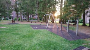Un parc avec des balançoires, des bancs et une statue de cheval.