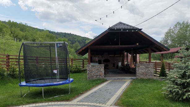 Un pavillon couvert doté d’une cheminée en briques, d’un trampoline et d’un chemin pavé menant à celui-ci.