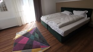 Une chambre à coucher avec un lit, une fenêtre avec des rideaux, un radiateur et un tapis coloré.