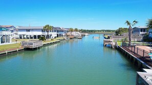 A canal with waterfront properties, docks, and a clear blue sky. - Channel Cat - Gorgeous Cherry Grove Channel House with Pool (North Myrtle Beach)