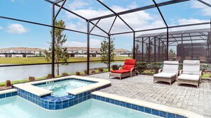 A pool area with a hot tub, lounge chairs, and a view of a lake and buildings.