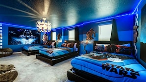 Ein Star Wars-Schlafzimmer mit mehreren Betten, Star Wars-Postern und blauer LED-Beleuchtung.