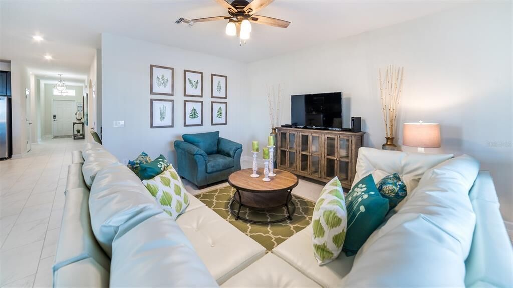 A modern living room with a sofa set, a coffee table, a television, and framed artwork on the wall.