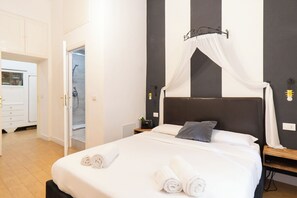 Habitación de hotel con cama, mesita de noche, armario y baño con ducha.