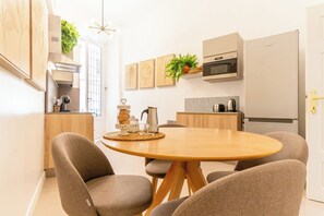 Una cocina moderna con una mesa redonda, sillas y una cafetera.