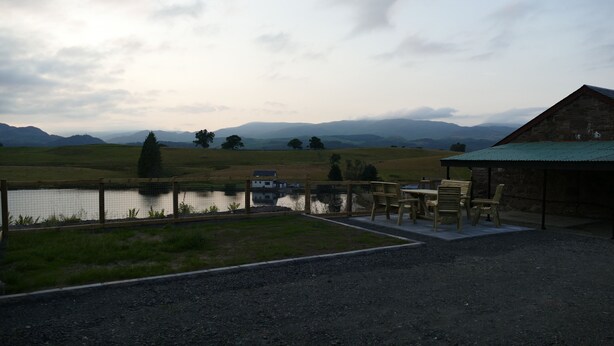 A rustic outdoor seating area with a view of a lake and distant mountains. - The Annexe at Loch View Farm will take your breath away (Crieff)