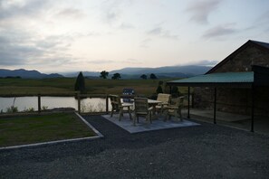 A patio with a table and chairs overlooking a lake, with mountains in the background. - The Annexe at Loch View Farm will take your breath away (Crieff)
