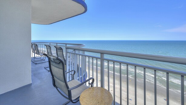 A balcony with a view of the ocean, equipped with chairs and a small table. - Grand Atlantic 1901 - 4 Bedroom Ocean Front Condo (Myrtle Beach)