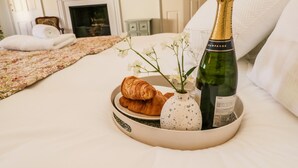Un lit avec un plateau contenant une bouteille de champagne, un croissant et un vase de fleurs.