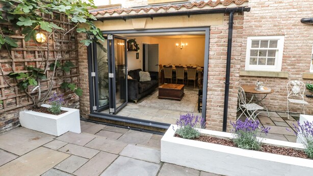 Une maison en briques avec un patio, un coin repas et une porte-fenêtre coulissante donnant sur le salon.