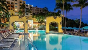A pool area with lounge chairs, palm trees, and a building with multiple balconies. - 2 BD/2 BA Beach Front Marriott Frenchman's Cove Condo St Thomas...SLEEPS 8! (St Thomas)