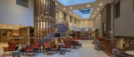 A spacious lobby with a central spiral staircase, multiple seating areas, and a skylight.